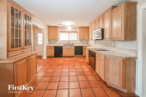 A kitchen with wooden cabinets and tile flooring.