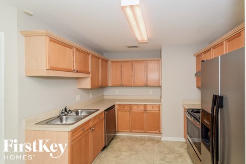 A kitchen with wooden cabinets and a black refrigerator.