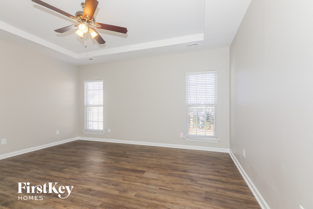 the spacious living room with a ceiling fan and wood flooring