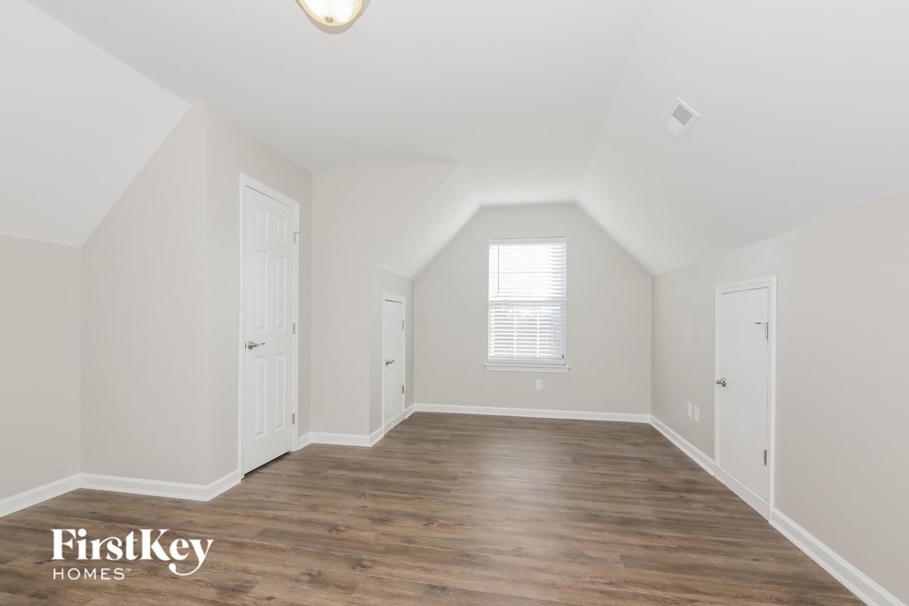 the living room of a home with white walls and a wooden floor