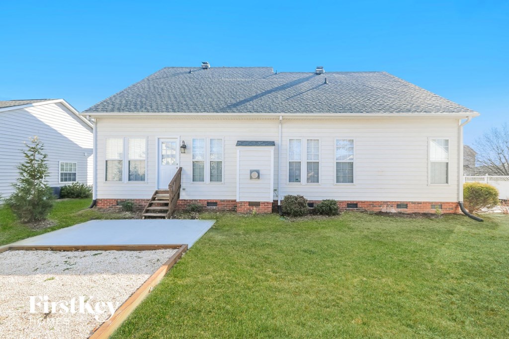 the front of a white house with a yard and a ramp