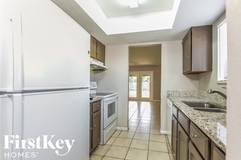 a kitchen with white cabinets and a white refrigerator and a sink