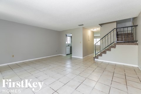 a spacious living room with a staircase and a tile floor