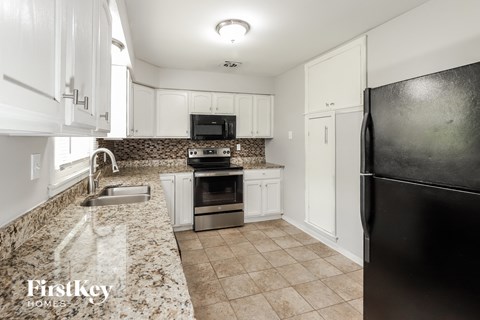 a kitchen with white cabinets and granite counter tops and black appliances