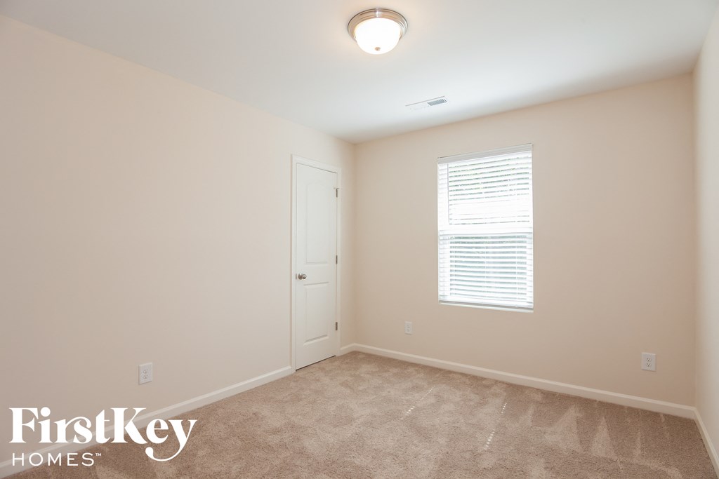 a bedroom with beige walls and carpet and a white door