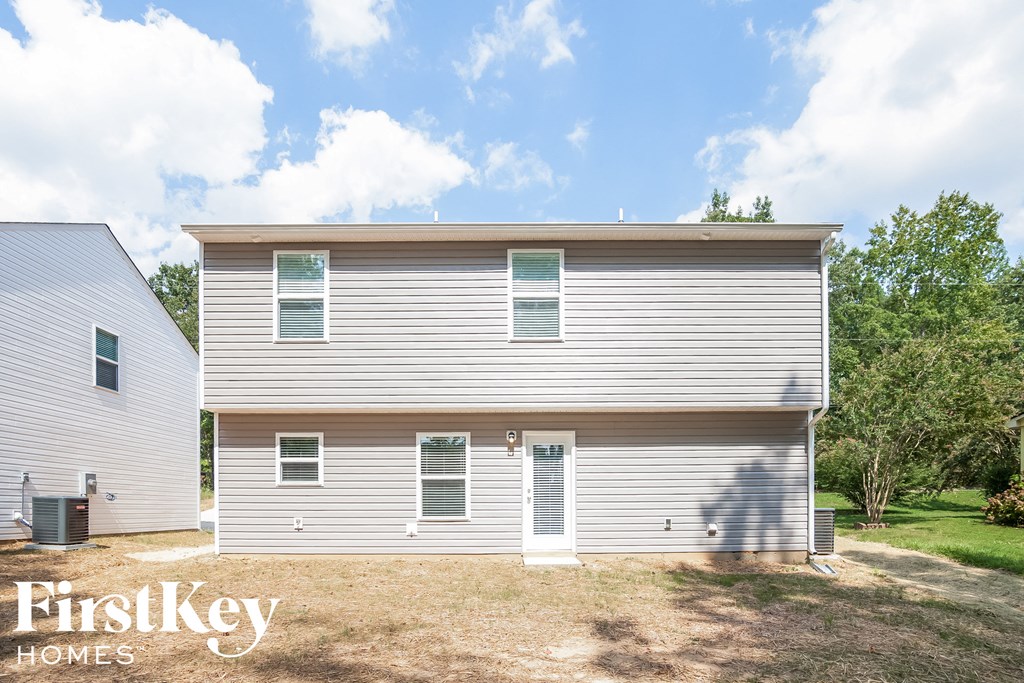 the front of a white house with a lawn and trees