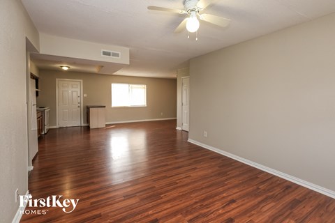 A spacious room with wooden floors and a ceiling fan.