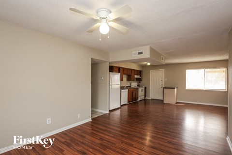 A room with a ceiling fan and wooden floors.