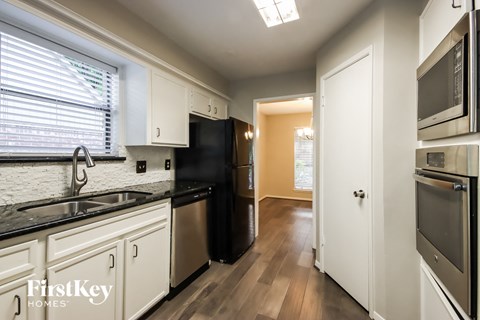 a kitchen with black counter tops and white cabinets and a black refrigerator