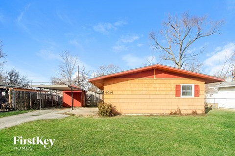 a small yellow house with a red door and a yard and a fence