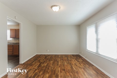 an empty living room with wood flooring and a window