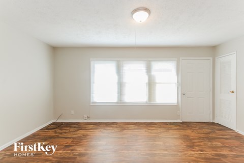 the living room of an empty house with wood floors and a window