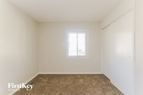 a bedroom with white walls and a window and a carpet