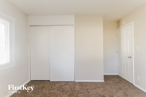 a bedroom with two white closets and a carpeted floor