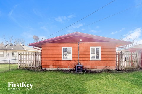a small red house with a yard and a fence
