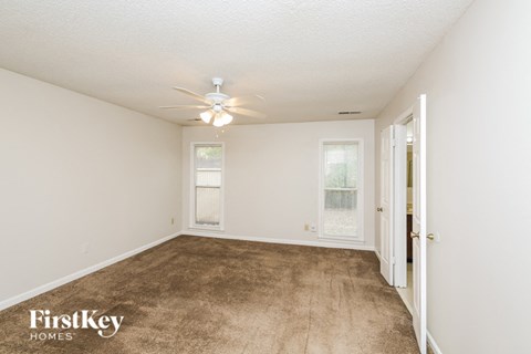a spacious living room with carpet and a ceiling fan