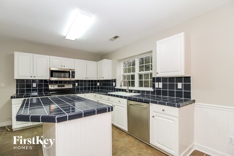 A kitchen with white cabinets and a black tile backsplash.