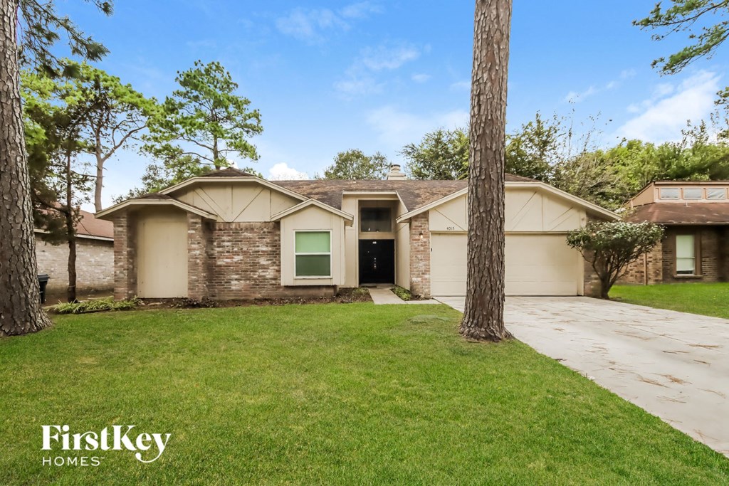 a beige and tan house with a yard and trees