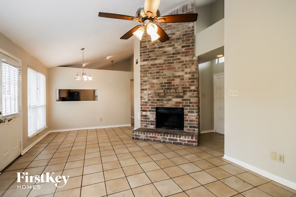 a living room with a brick fireplace and a ceiling fan