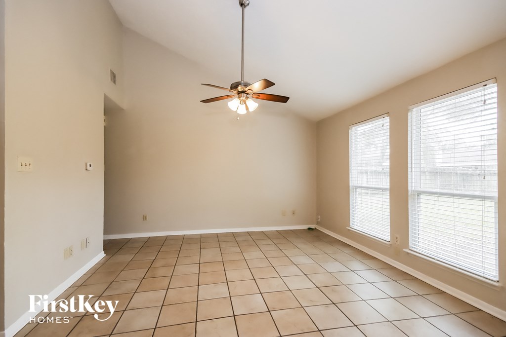 an empty living room with large windows and a ceiling fan