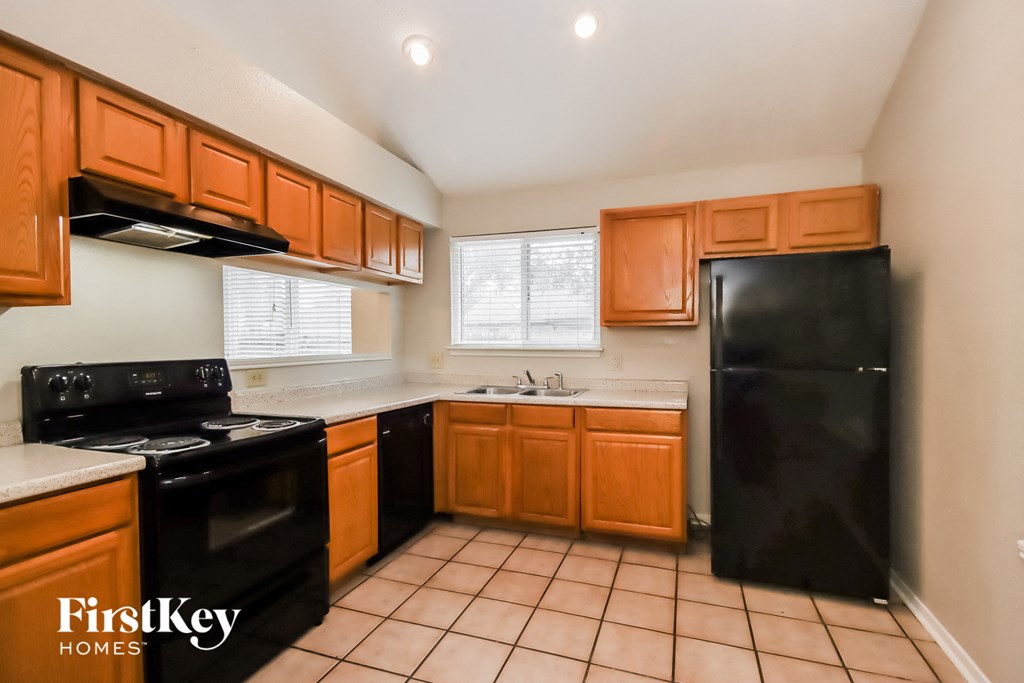 an empty kitchen with black appliances and wooden cabinets