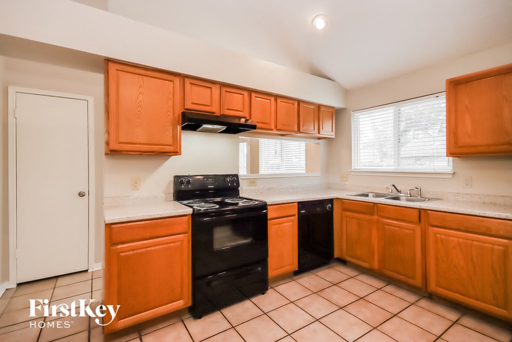 a kitchen with wood cabinets and black appliances and a sink