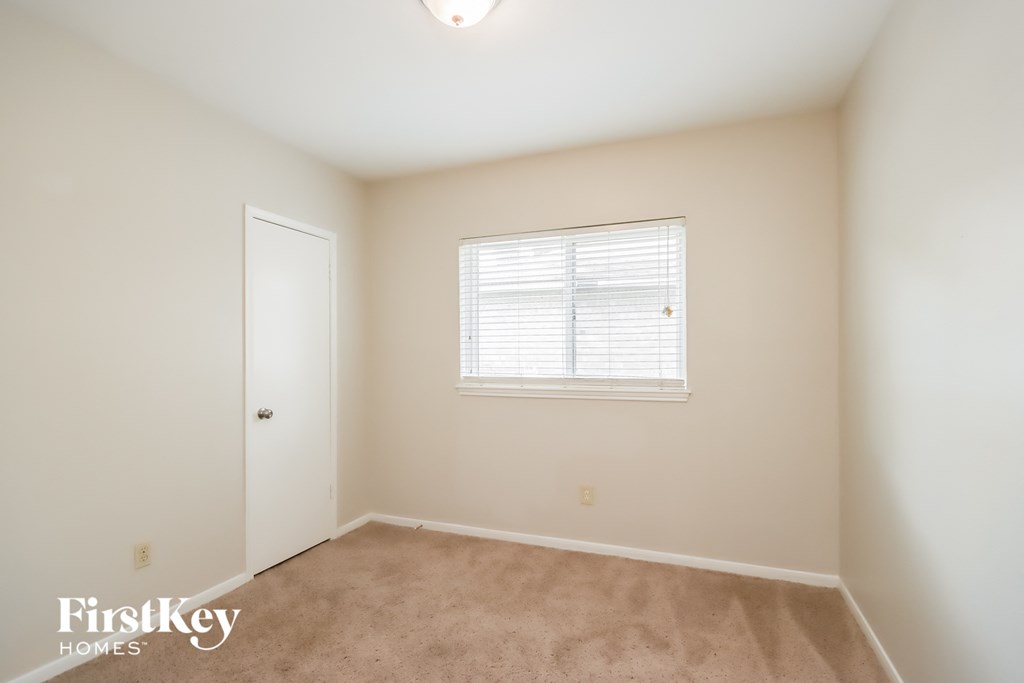a bedroom with carpet and a window and a door