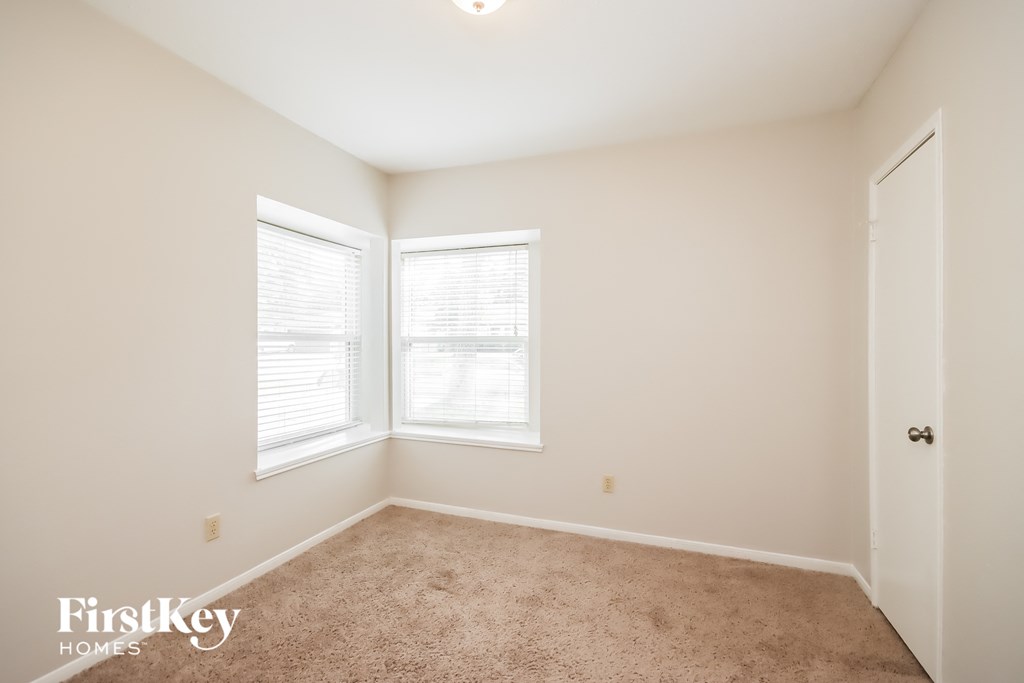 an empty room with two windows and a door
