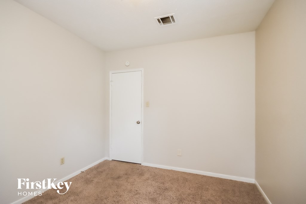 a bedroom with white walls and carpet and a white door