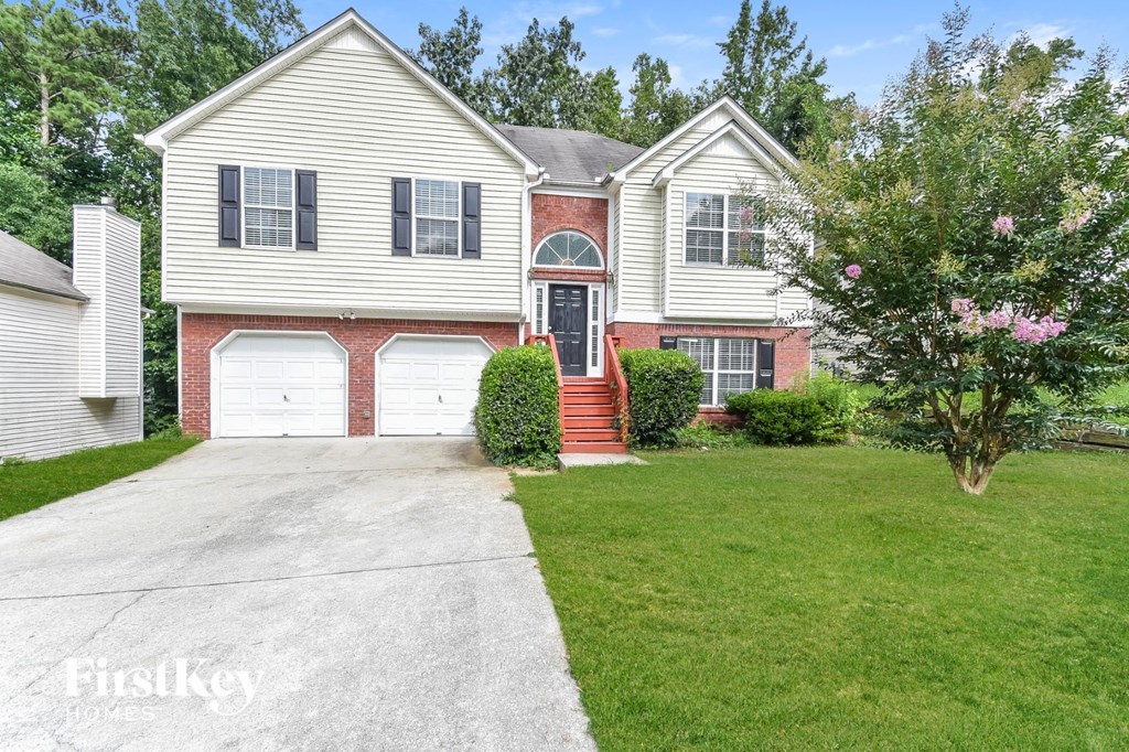 a white house with red brick and white garage doors