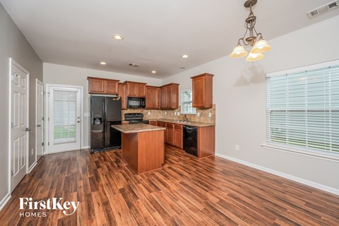 A kitchen with wooden floors and a black refrigerator.