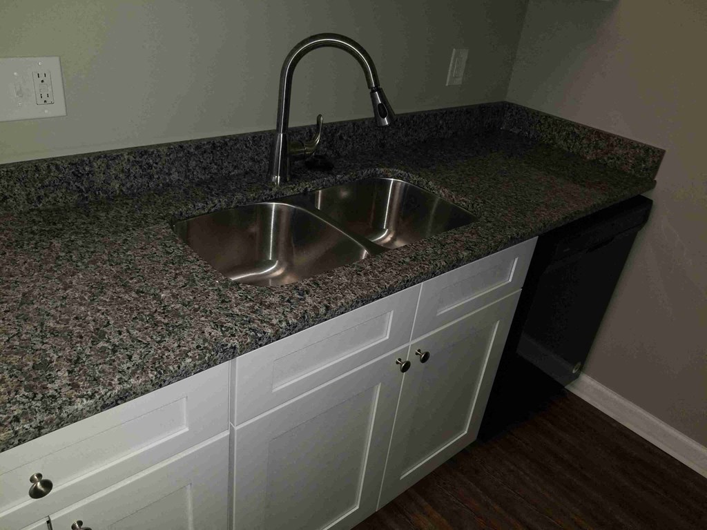 A kitchen counter with a granite countertop and two sinks.