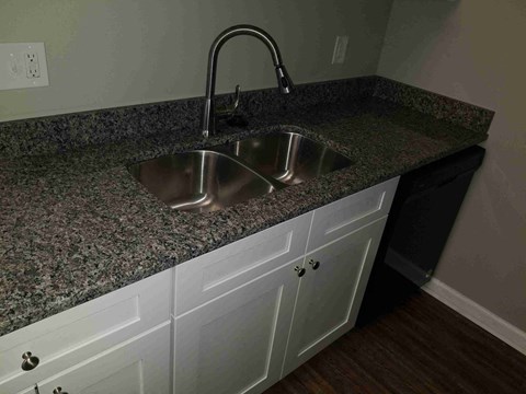 A kitchen counter with a granite countertop and two sinks.