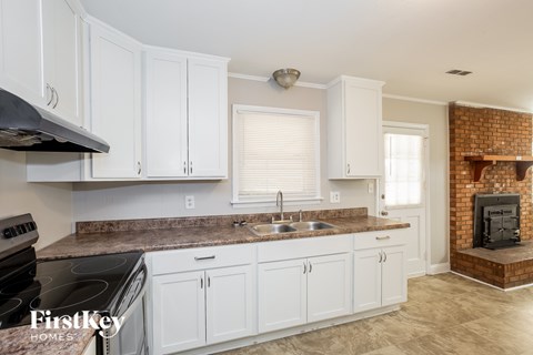 A kitchen with white cabinets and a brick fireplace.