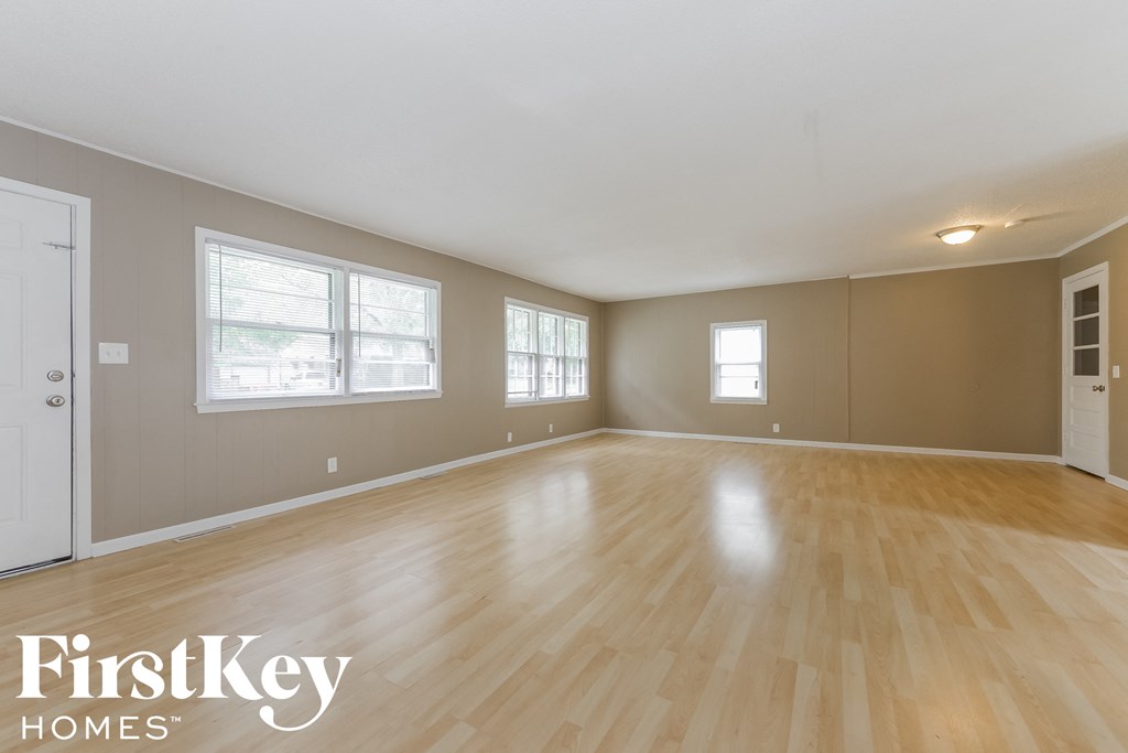 A spacious room with wooden flooring and white walls.