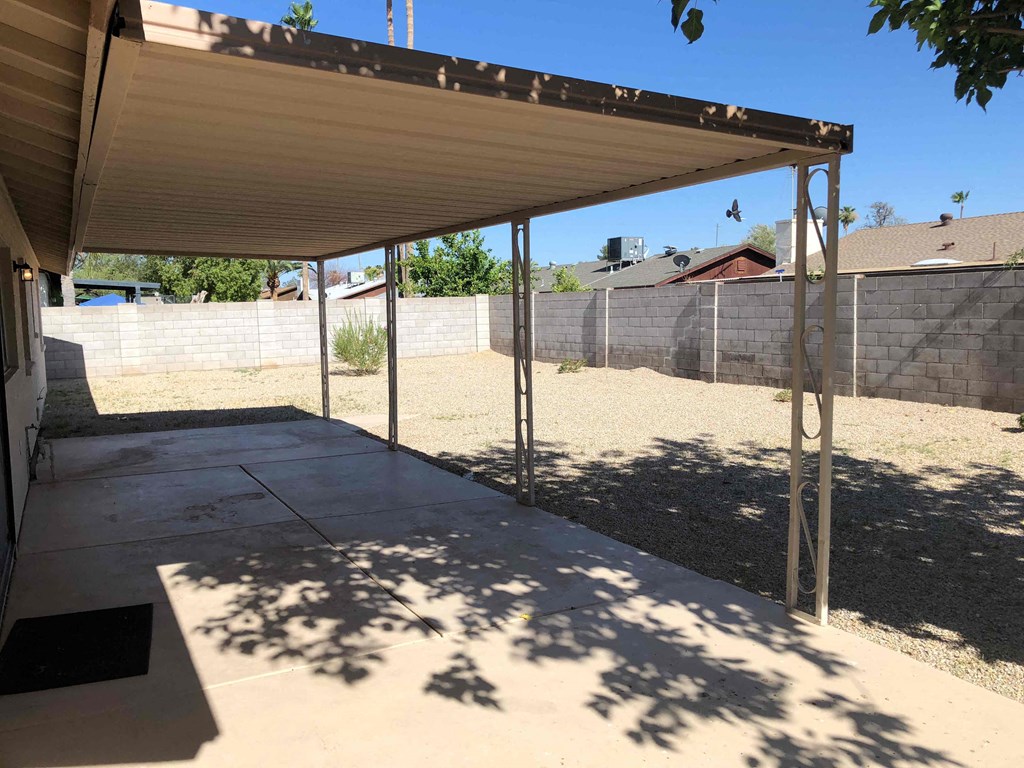 a patio with a shade canopy in a backyard