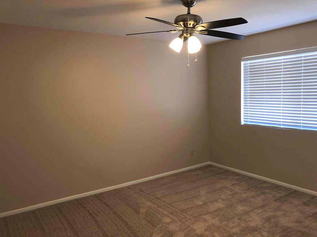 a bedroom with a ceiling fan and a window