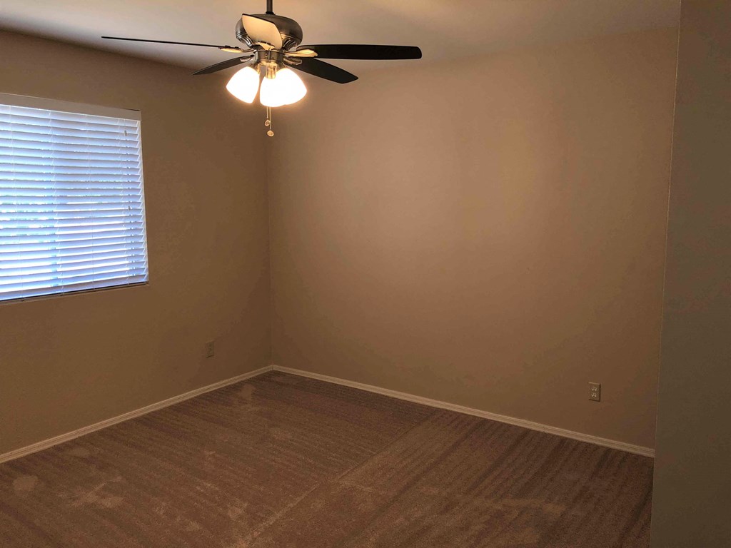 a empty room with a ceiling fan and a window