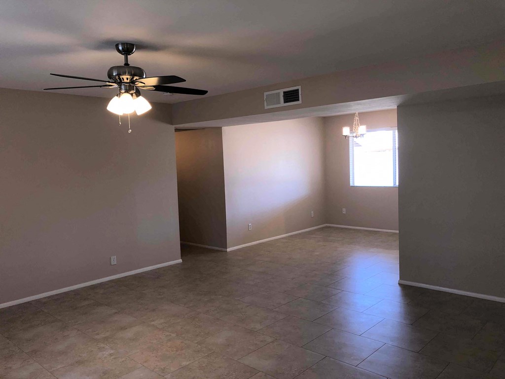 an empty living room with a ceiling fan and tiled floors