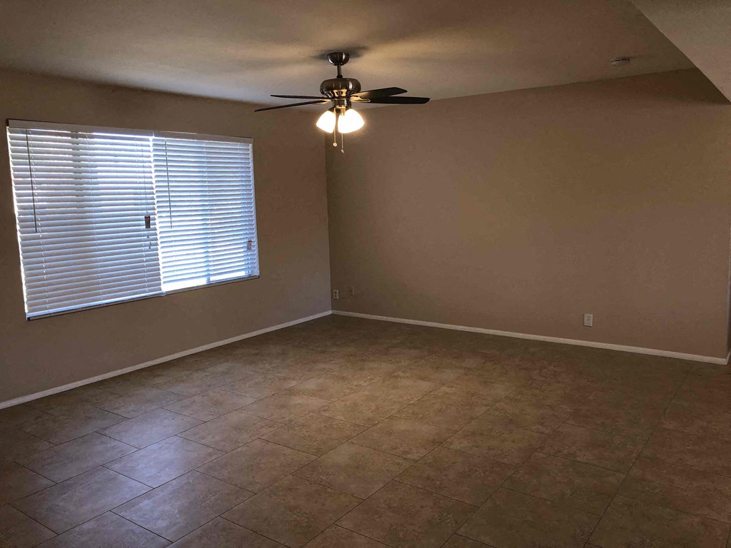 an empty living room with a ceiling fan and a window