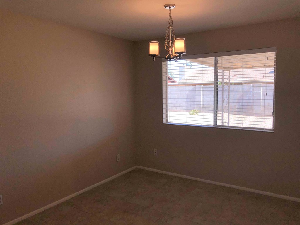 an empty room with a window and a chandelier