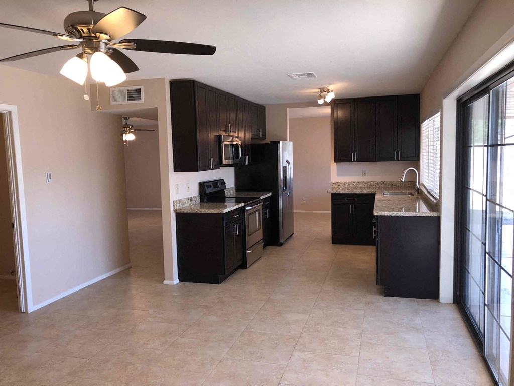 a kitchen with black cabinets and a ceiling fan