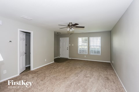 a spacious living room with carpet and a ceiling fan