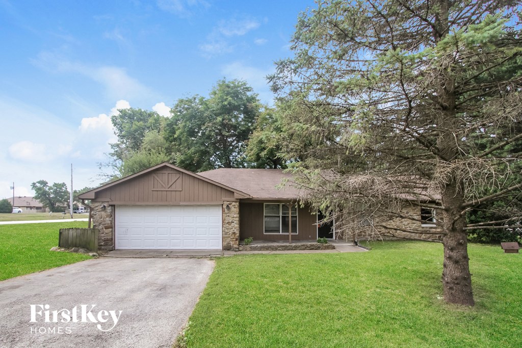 a home with a white garage door in front of a green lawn and trees