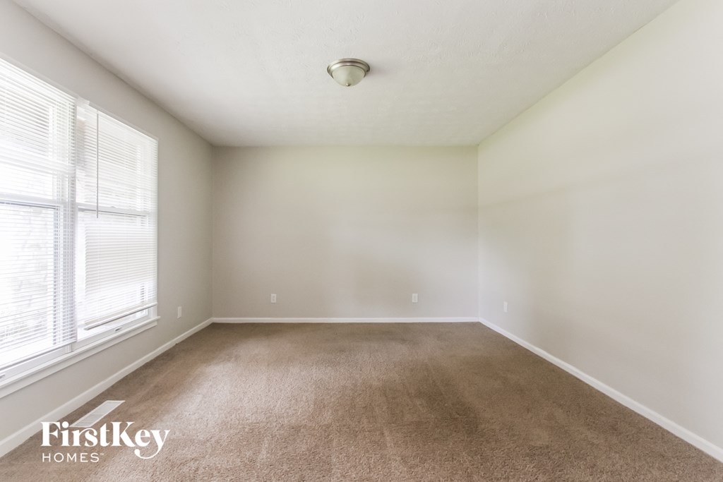 an empty living room with a large window and carpet