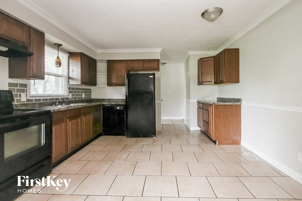 an empty kitchen with black appliances and wooden cabinets