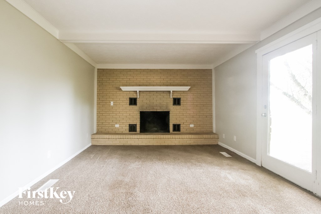 an empty living room with a brick fireplace and white walls