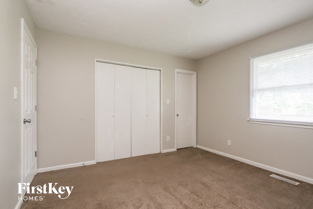 a bedroom with a carpeted floor and a closet and a window