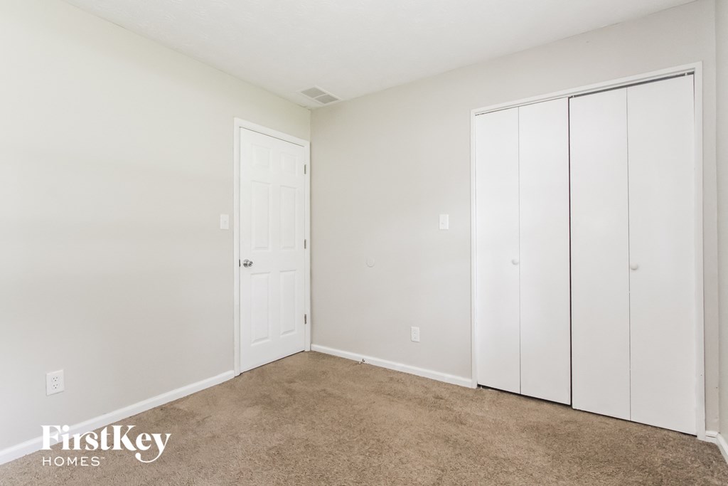 a bedroom with a carpeted floor and white closets