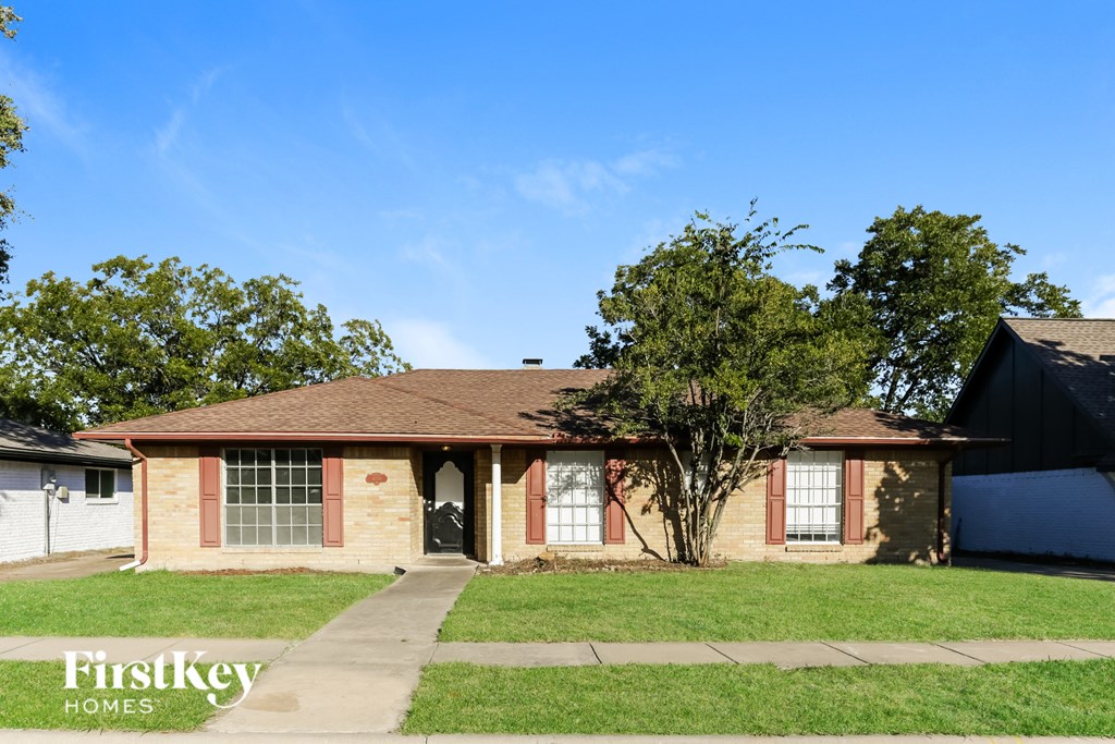 A house with a brown roof and a tree in front of it.